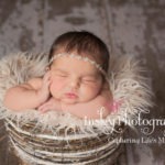 color newborn pose baby in basket with hand on cheek