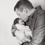 newborn baby girl safe in daddy's arms
