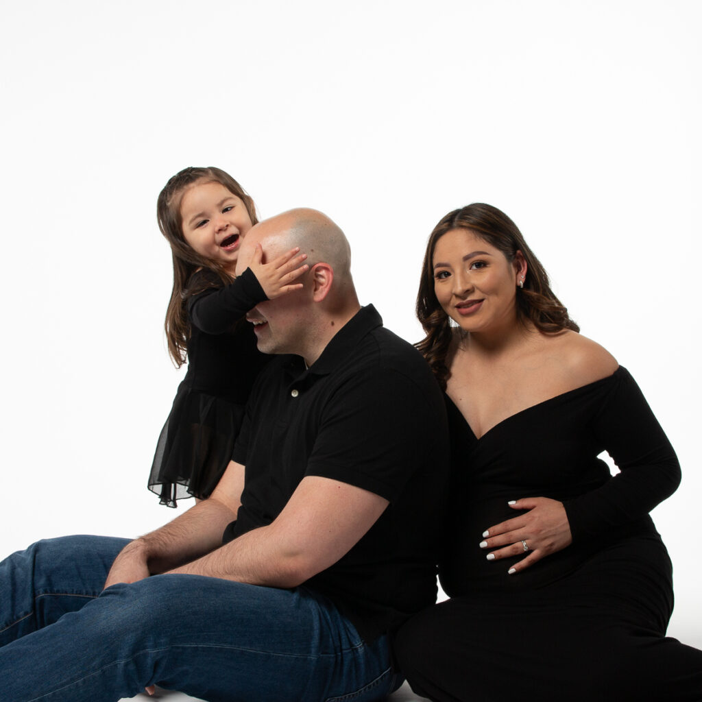 Silly capture of a toddler hugging her Dad's head and not sitting in the family portrait. father's day portraits are coming to Insley Photography!