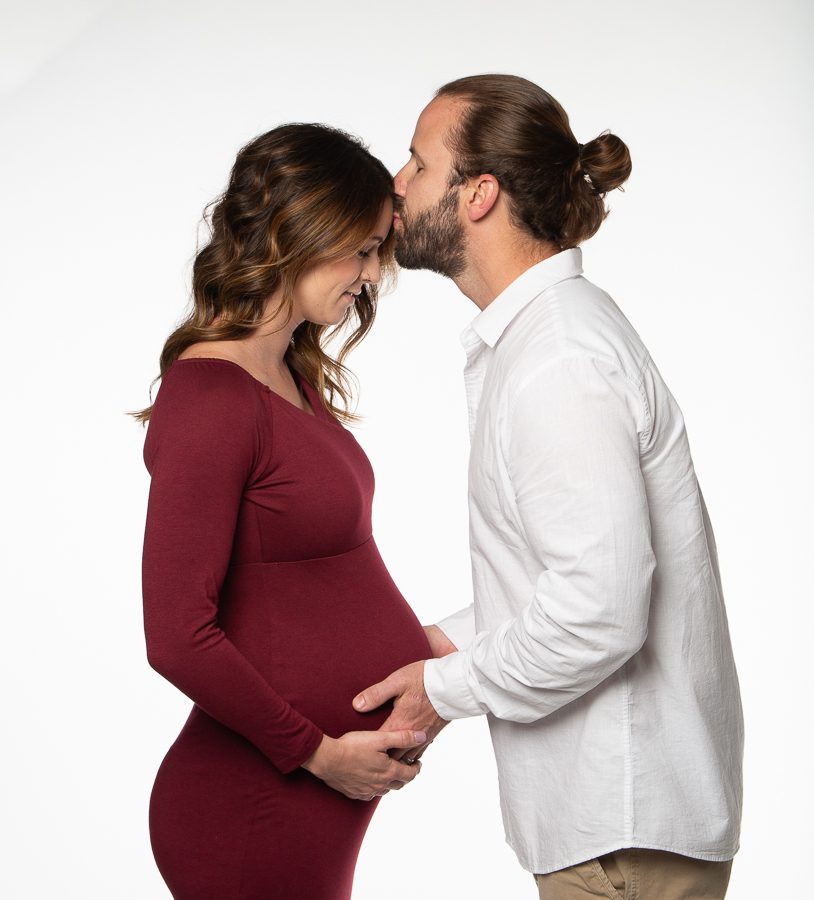 expecting couple maternity pose with gentle forehead kiss
