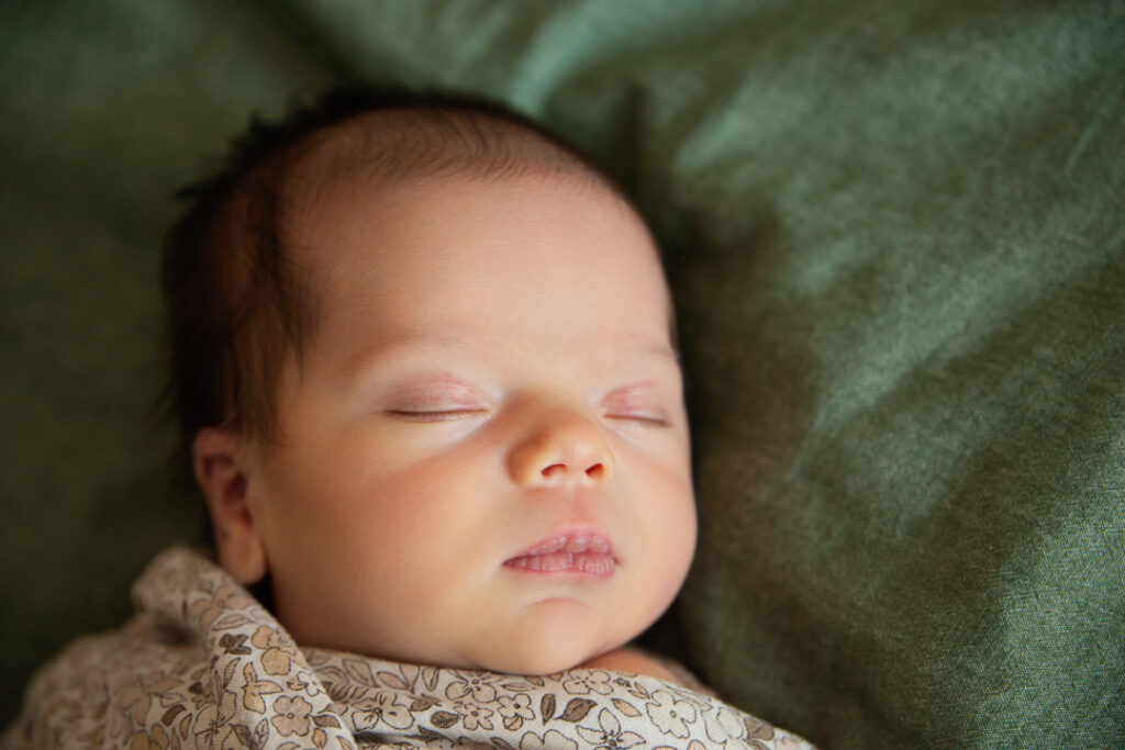 close up of precious new baby girl sleeping peacefully on a green comforter, Charlotte NC newborn photo.