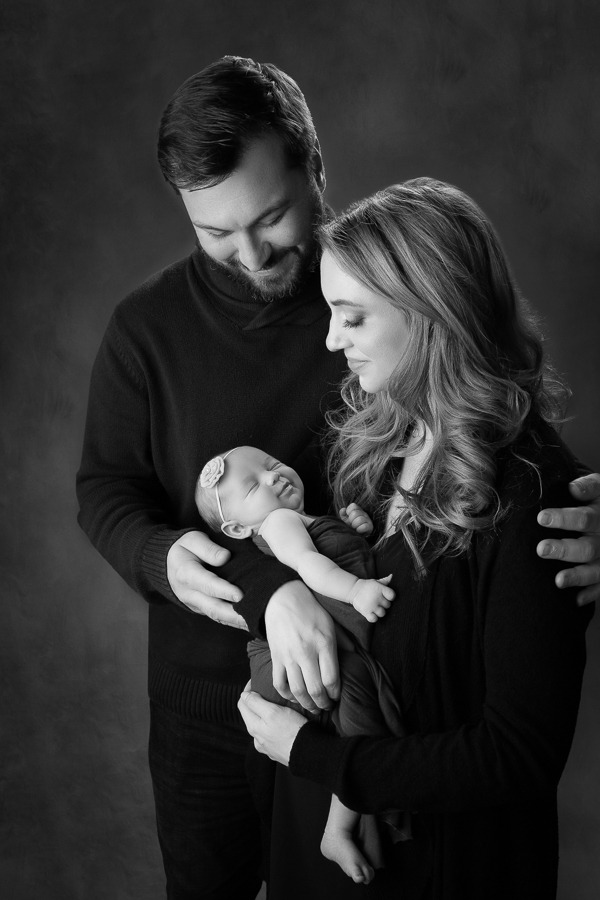 parents holding their newborn daughter during their studio portrait session 