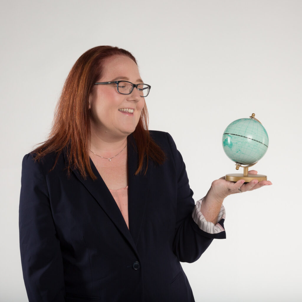 Disney planner Red haired fair skinned woman holding globe posing for a modern branding portrait. Created by Charlotte Headshot Photographer, alicia insley Smith 2024
